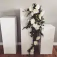 Set of three white pillars adorned with flowers.