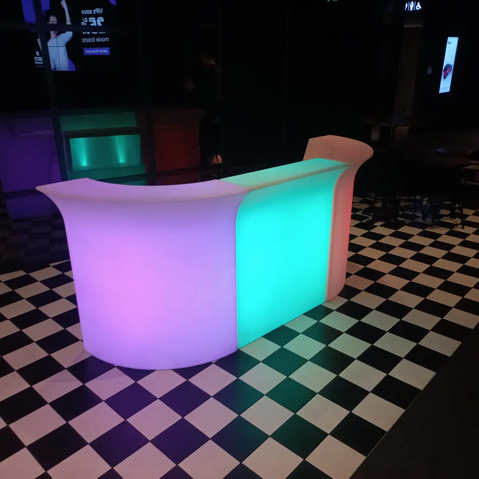 LED glow bar with curved modular sections illuminated in changing colours, set in a dark indoor event space with checkerboard flooring
