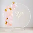 A let's party sign adorns a pink and gold balloon arch.