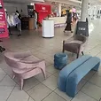 Pink velvet Lola arm chair set up in a conference foyer alongside a sky blue Apollo bench seat and ottoman.