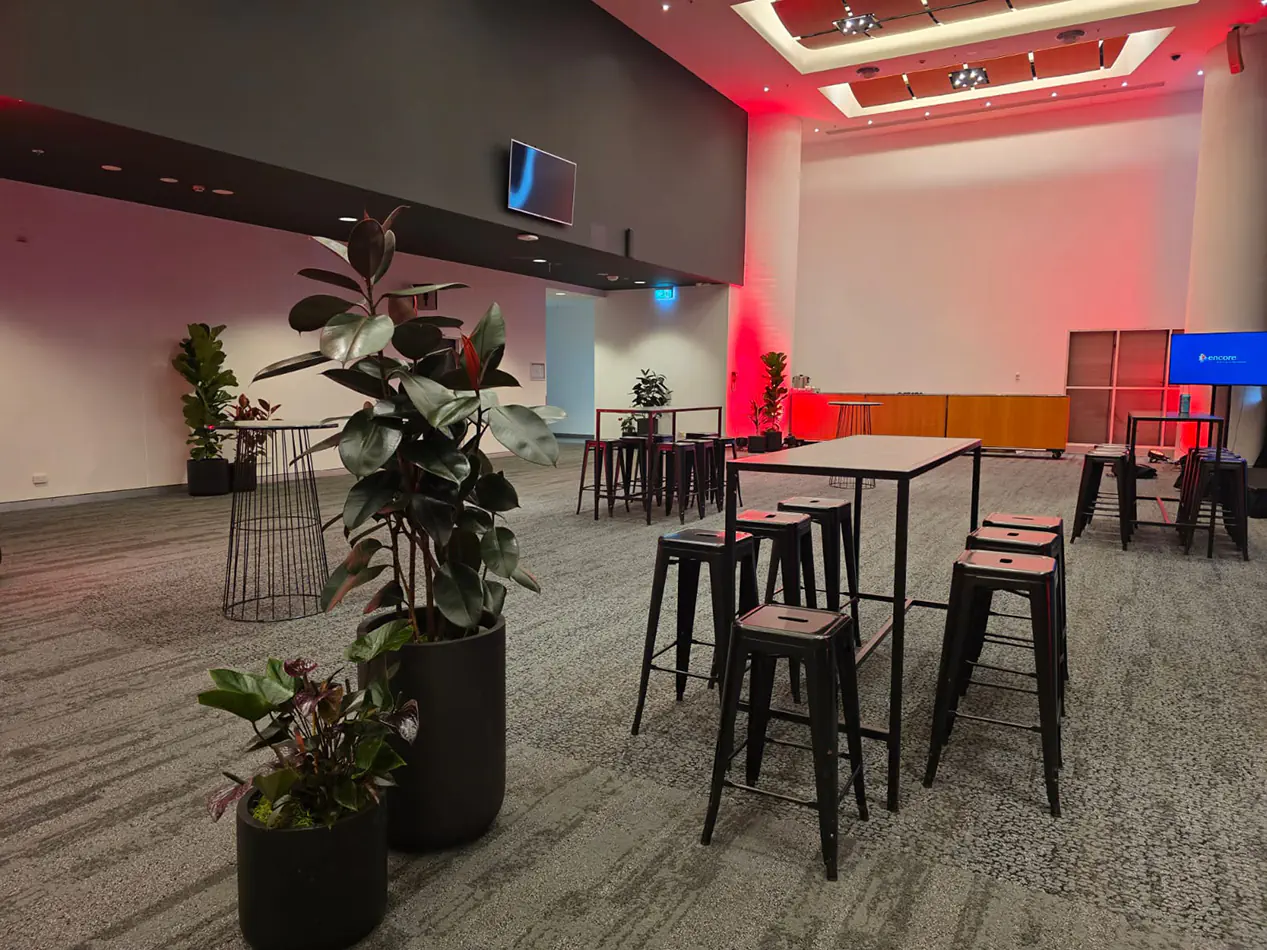 Modern corporate event space with black tapas bar tables, black stools and ambient red lighting throughout the venue