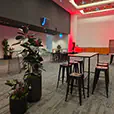 Modern corporate event space with black tapas bar tables, black stools and ambient red lighting throughout the venue