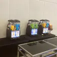 Multiple slushie machines arranged on tables as a refreshment station with different coloured frozen drinks at an event