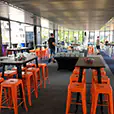 Orange metal bar stools arranged around cocktail tables in a modern indoor event venue with high tables and casual seating