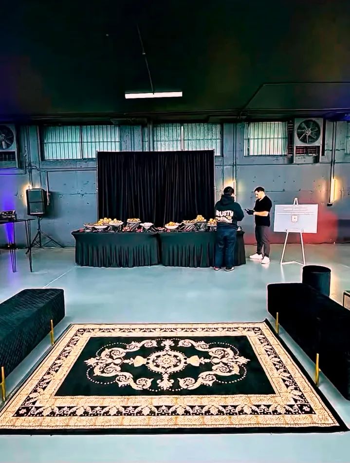 Black drape backdrop behind a catering table in a warehouse event space.