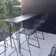 Black hairpin high bar table set up on a balcony with wire stools