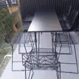 Hairpin high bar table with black top set up with wire chairs on a balcony