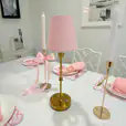 A pink shade table lamp on a table with decorations