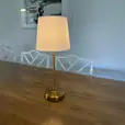 A white shade table lamp on a timber table
