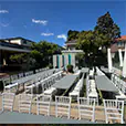 Outdoor event setup with long grey trestle tables and white Chiavari chairs arranged in a private backyard venue