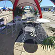 White wire cocktail tables and matching stools arranged at an outdoor event setup with open surroundings and coastal backdrop