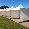 Outdoor row of white pop-up marquees with side walls installed for event booths and temporary vendor spaces
