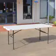 A white plastic trestle table in front of a building.