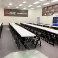A room with plastic trestle tables and chairs set up for a meeting.