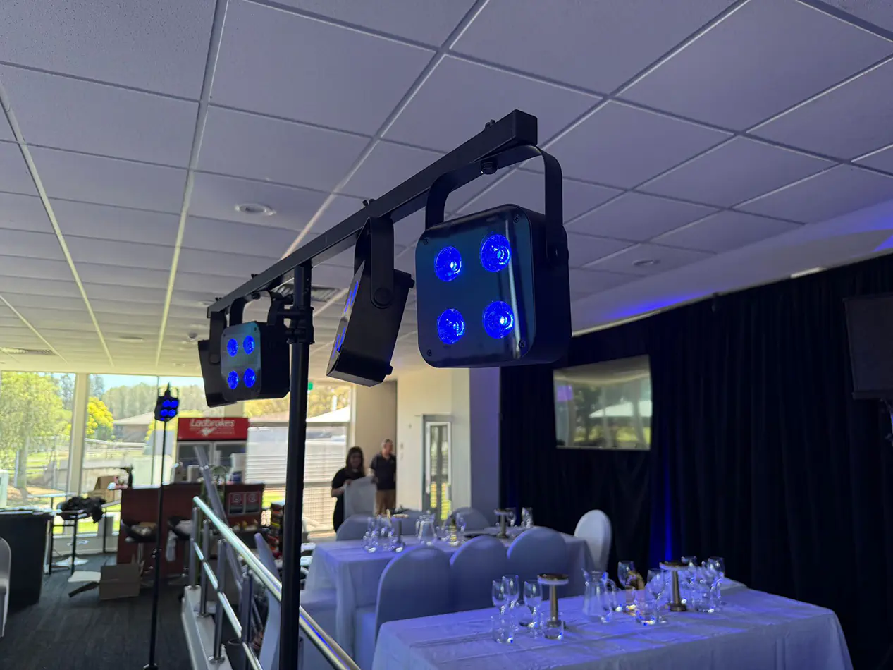 Portable event lighting rig with blue LED light fixtures illuminating a decorated dining and function venue