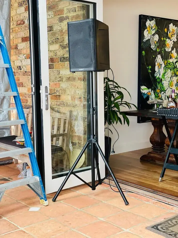 Portable PA speaker mounted on stand positioned near doorway in residential setting for small home event audio setup