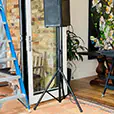Portable PA speaker mounted on stand positioned near doorway in residential setting for small home event audio setup