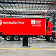 Portable PA system with speakers on stands and microphone setup positioned in front of Australia Post truck inside large warehouse event space