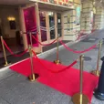 Three metre red carpet runner laid at a theatre entrance and lined with gold bollards and red velvet ropes