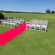 A stunning wedding ceremony set up on a golf course, complete with a luxurious 6m red carpet hire.