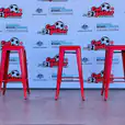 Three red Tolix stools in front of a banner.