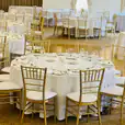 A spacious room furnished with round timber banquet tables and chairs for hire.