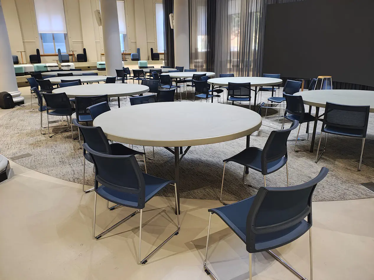 Conference room setup with round banquet tables and chairs arranged for group seating in a large indoor space