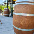 Rustic wooden wine barrel cocktail tables placed in an outdoor venue seating area with covered veranda and surrounding furniture