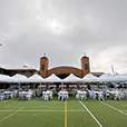Long row of white pop-up marquees with outdoor dining tables and chairs arranged for a school or community event