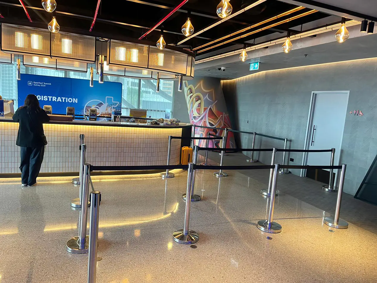 Silver tensa barrier queue setup positioned in front of an event registration counter inside a modern venue foyer