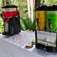 Slushie machine hire with multiple flavour dispensers in red, yellow and green set up on a table with cups for outdoor event service