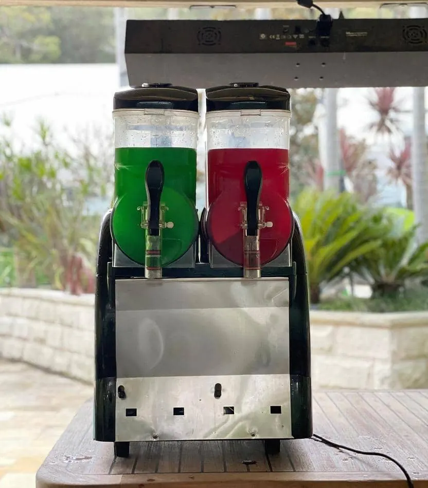 Two soda dispensers, one functioning as a slushie machine from Package 2, are sitting on top of a table.