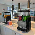 Slushie machines on a counter with colourful drink dispensers filled with frozen beverages in an indoor event setting