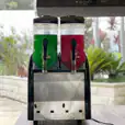 Two soda dispensers sitting on top of a table, available for Slushie Machine Hire.