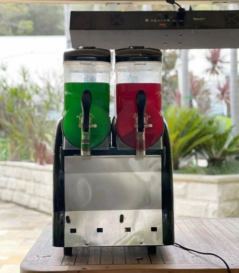 Two soda dispensers sitting on top of a table, available for Slushie Machine Hire.