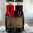 Two slushie machines on a table in front of a window, serving up to 240 drinks.