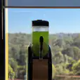A green juice machine sitting in front of a window, offering 60 drinks.