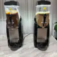 Slushie Machine Hire: Pkg 1 - Two ice cream machines on a marble counter serving up to *60 drinks*.