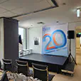 Office event stage setup with speakers on stands, small platform stage and seating arranged for a presentation in a corporate space