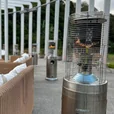 Stainless steel outdoor area heater providing warmth beside lounge seating on a covered event terrace