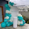 White balloon garland styled around a white round backdrop with personalised lettering, paired with a matching white plinth for a clean and elegant event display.