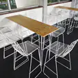 Timber top hairpin table surrounded by white wire stools