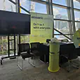 TV hire setup for a corporate trade show display with branded signage, seating, event table and city views through large glass windows