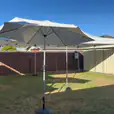 A backyard with a white market umbrella and chairs.