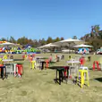 A group of tables and chairs set up in a grassy field, perfect for Market Umbrella Hire.