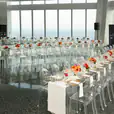 A long table is set up in a room with a view of the city, featuring Victorian Ghost Chair Hire.