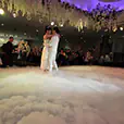 Bride and groom dancing on a low-lying dry ice cloud effect during a wedding reception with floral ceiling installations