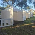 White 3x3m pop-up marquees with three-sided walls arranged as sheltered event booths on a grassed park site