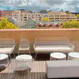 A balcony with white wire furniture including the White Arrow 3 Seater Sofa and a city view.