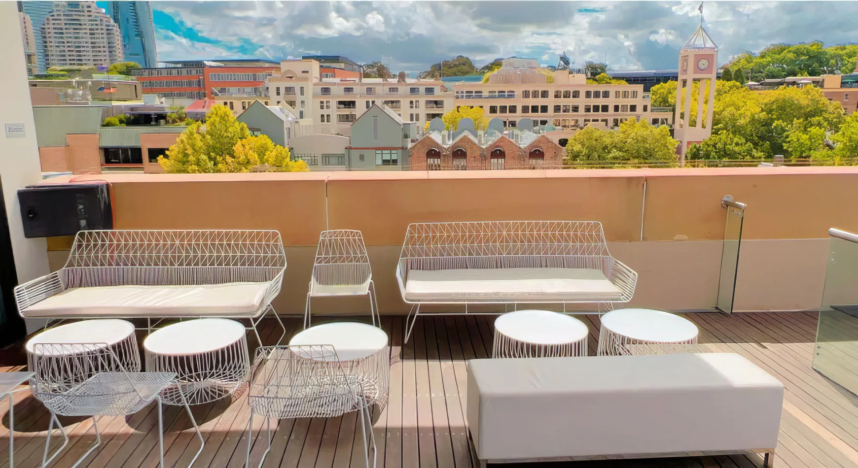 A balcony with white wire furniture including the White Arrow 3 Seater Sofa and a city view.